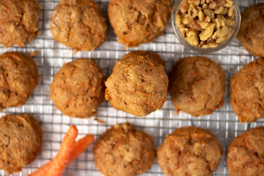 A cooling rack filled with fresh baked carrot cookies ready to be frosted.
