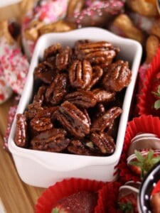 Close up of glazed pecans on a dessert board.