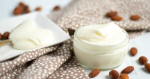 Elegant homemade almond flavored icing with whole almonds around the bowl of icing