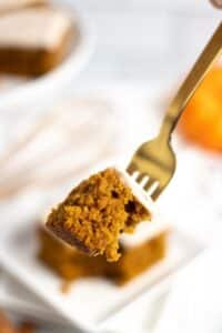 A fork full of pumpkin cake with frosting