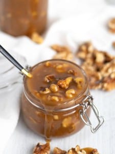 A jar of walnut caramel sauce with a spoon in it.