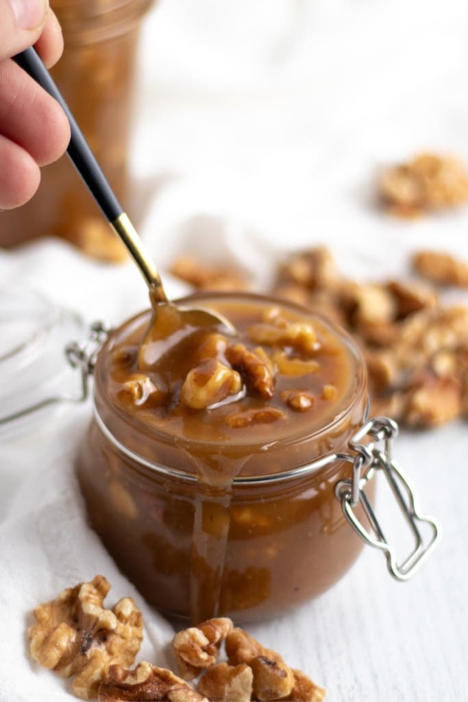 Easy Caramel Walnut Sauce in a glass jar with a spoon Kitchen Cents Recipe