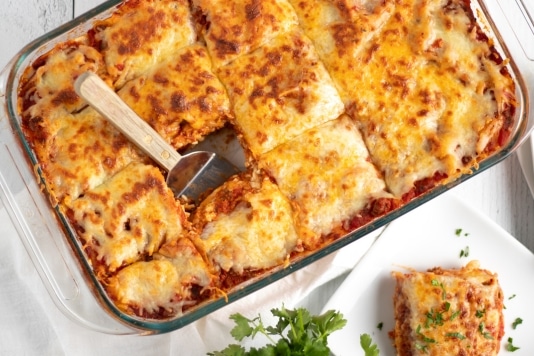 A 9x13 pan of easy lasagna cut into portions and ready to eat