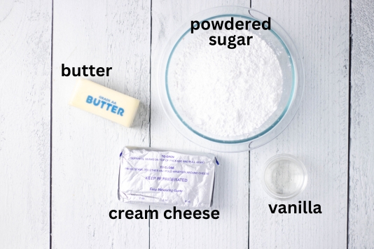powdered sugar, butter, cream cheese and vanilla pictured as ingredients needed for cream cheese frosting.