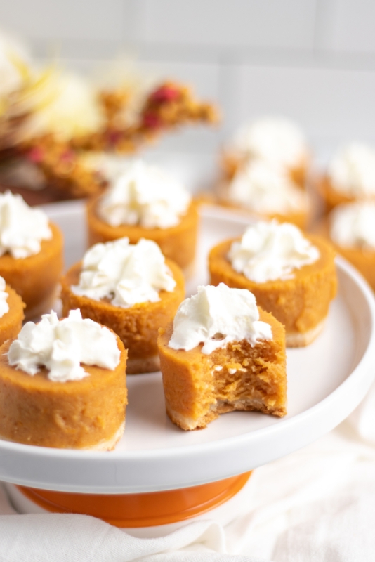 Plate of mini pumpkin pies with a bite taken out of one pie.